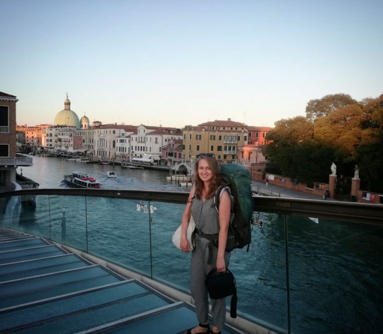 Maria Kudryashova mit Reiserucksack und Kameratasche auf einer Brücke in Venedig